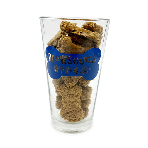 A clear glass labeled Filled Pint by Brewscuits is filled with brown, crunchy natural dog treats made from spent beer grains—a perfect gift for pet owners.