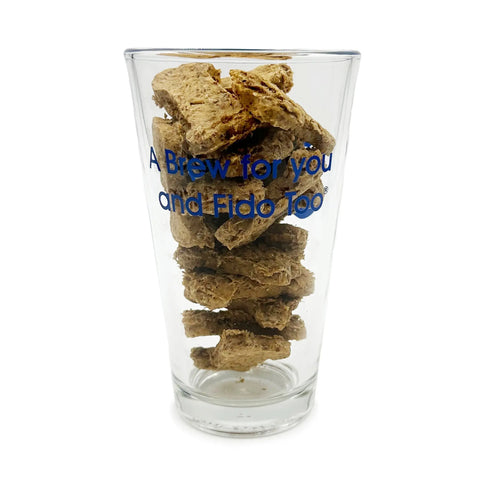 The Brewscuits Filled Pint is a clear glass with blue A Brew for you and Fido Too text, filled with stacked natural dog treats—an ideal pet owner gift from Brewscuits, shown on a plain white background.