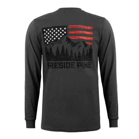 The Alaska Yellow Cedar - Slate by Fireside Pine is a black organic cotton long sleeve shirt with a back graphic: stylized American flag (red stripes), mountains, pine trees, and Fireside Pine text in black and white.