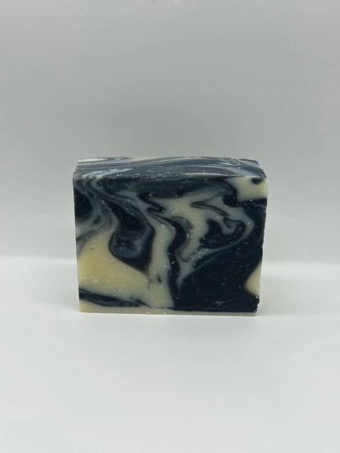 The O’ Suds Bar by Five O Clock Co.—a handcrafted rectangular soap with a marbled black and cream design—stands upright against a white background. Made in small batches with nourishing ingredients for a gentle, natural cleanse.