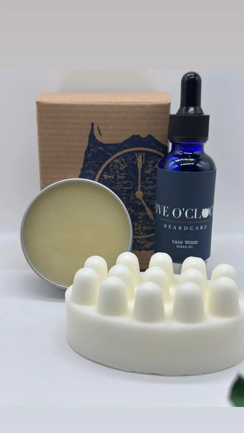 The Five O Clock Co. Beard Care Kit includes a blue dropper bottle of beard oil, a round tin of beard balm, a textured white soap bar, and comes in a stylish box with a clock design.
