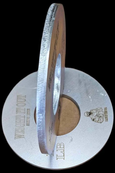 Two Weight It Out Fractional Solid Steel Mini Olympic Weight Plates, each with a central hole and engraved text plus a muscular figure, are interlocked upright on a black background—ideal for gradual weight increase.