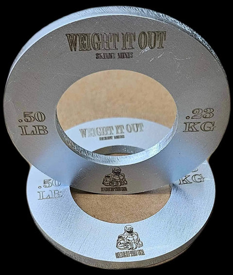 Two Weight It Out Fractional Solid Steel Mini Olympic Weight Plates (0.50 LB/0.23 KG each) are stacked beside a muscular figure—perfect for precise weight increases on your barbell.