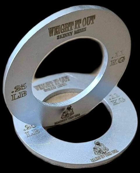 Two silver, donut-shaped Fractional Solid Steel Mini Olympic Weight Plates by Weight It Out, inscribed with 0.25 LB and 1.1 KG, stacked on a black background—perfect for gradual weight increase on your Olympic bar.