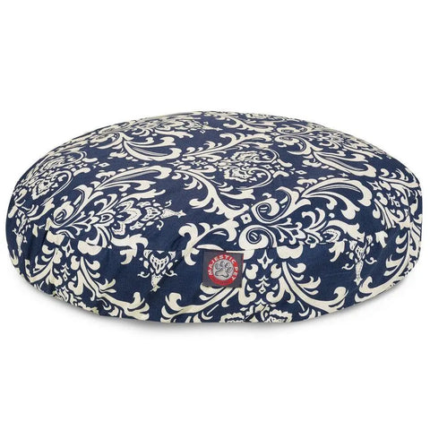 The Majestic Pet French Quarter Round Dog Bed features a blue and white ornate floral pattern, a small red and white paw print patch, washable fabric, and a removable cover for easy cleaning.