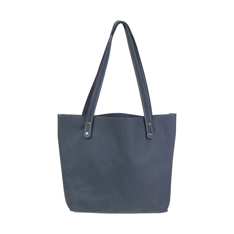 The Fore Street Tote Bag by Rogue Industries is a simple dark blue full-grain leather tote with two long handles and visible stitching, pictured against a white background.