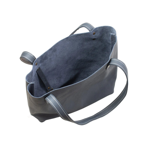 The Rogue Industries Fore Street Tote Bag, crafted in Maine from dark blue full-grain leather with suede interior and two shoulder straps, is shown open and empty from above on a white background—combining elegance and durability.
