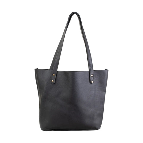The Fore Street Tote Bag by Rogue Industries is crafted from black full-grain leather, featuring two shoulder straps with metal rivets and a slightly textured surface, offering timeless minimalist style.