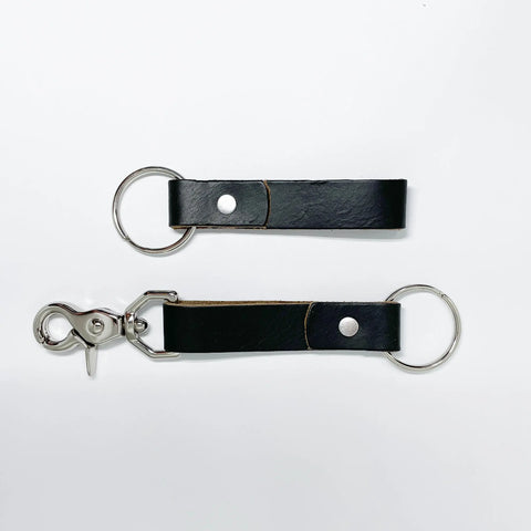 Two Rogue Industries Leather Key Chains in black top-grain cowhide with metal rivets—one has a keyring, the other has a keyring and swivel clasp. Both are shown laid flat on a white background.