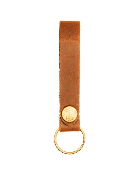 The Homestead Brand Standard Key Fob No. 1603 is a brown USA-tanned leather keychain with a gold metal ring and round embossed gold emblem, featuring solid brass hardware for lasting durability, shown on a white background.