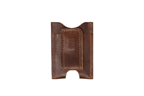 The Urban Southern Money Clip Wallet is a slim brown leather wallet with visible stitching, a central pocket, and an external money clip on the front.