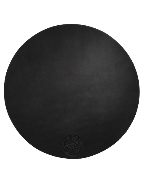 The Homestead Brand Leather Pot Holder No. 2001 is a large, round full grain leather pot holder with a subtle embossed logo near the bottom edge, shown against a white background—ideal for durable table protection.