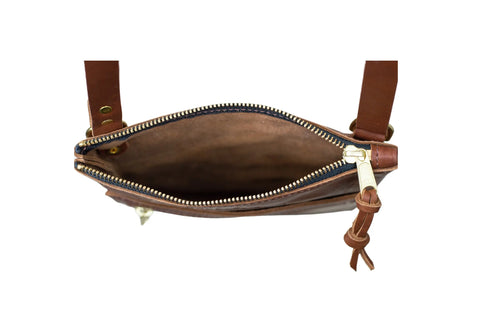 Top view of the Urban Southern Urban Slim Crossbody, an open brown leather bag with a zipper and attached shoulder strap—showing its empty interior. A perfect lightweight handbag for urban slim style.