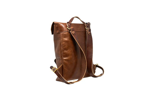 The Urban Southern Urban Rucksack in brown full-grain leather features adjustable straps, a top handle, brass hardware, and a structured yet slightly slouchy design—ideal for everyday adventures. Shown against a white background.