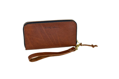 The Urban Southern Urban Zipper Wallet is a brown leather wallet with an accordion-style design, zippered closure, and wrist strap with gold clasp. Displayed on a white background, it features a subtle embossed logo on the front.