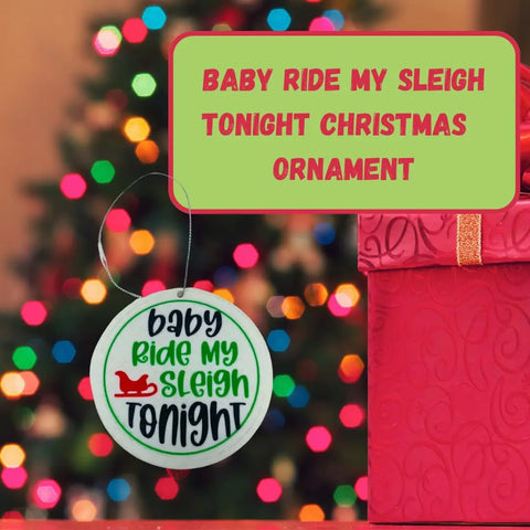 A round Chatelet Manufacturing Christmas ornament reading Baby Ride My Sleigh Tonight hangs near a red gift box—a funny gag gift and perfect Dirty Santa holiday ornament, made in the USA.