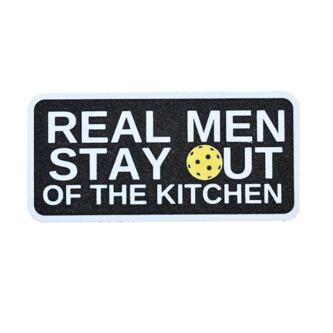 The Chatelet Manufacturing Pickleball Real Men Stay Out of the Kitchen fridge magnet features white text on black, with a yellow cookie as the “O” in “OUT”—a funny USA-made gift for any pickleball player.