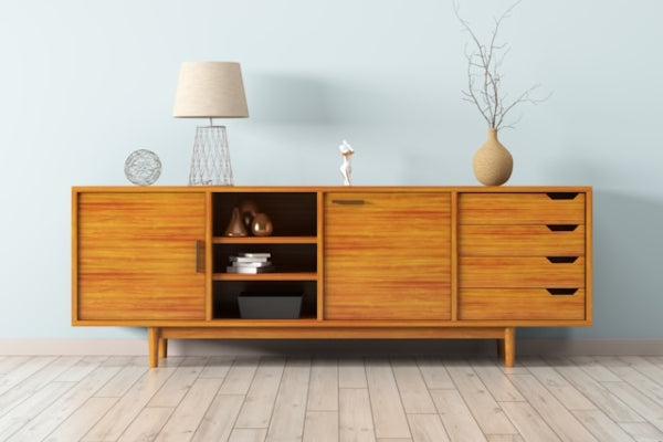 Wooden sideboard with decorative items against a light blue wall.