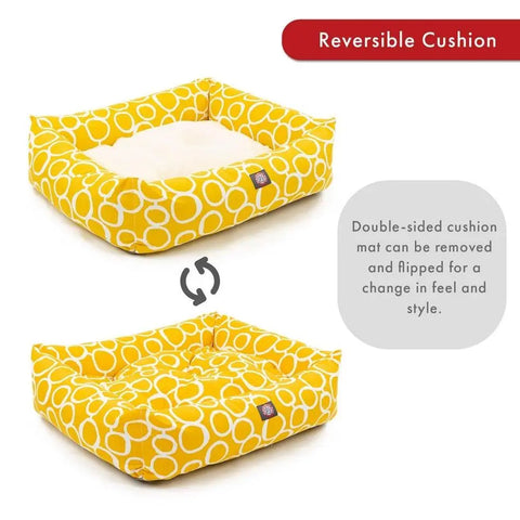 Two yellow Majestic Pet Fusion Luxe Bagel Beds with white circles are shown. The removable cushion is reversible, offering two looks and feels. Text notes the bed is machine washable, and an arrow highlights the reversible cushion feature.