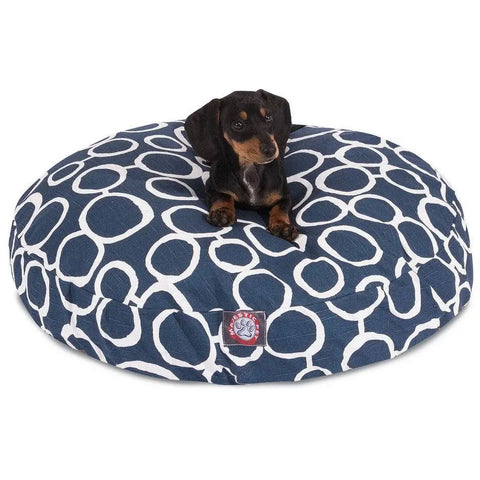 A small black and brown puppy rests on the Majestic Pet Fusion Round Dog Bed, which is navy blue with a white circular pattern and has a washable, removable cover for easy cleaning.