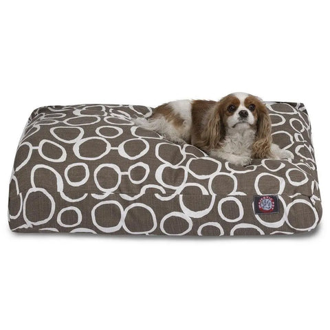 A small brown and white dog relaxes on the Majestic Pet Fusion Memory Foam Dog Bed, featuring a brown rectangular design with a white circular pattern and a washable cover for easy cleaning.