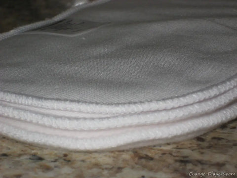 A close-up of Geffenbaby High Absorbers Cloth Diaper Inserts, featuring several white, oval-shaped layers with soft textured fabric and neat stitching, stacked on a granite countertop—ideal for eco-friendly diapering.