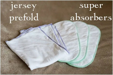 Two stacks of white cloth diapers are displayed on a brown surface. The left stack is labeled jersey prefold, while the right stack features Geffenbaby Super Absorbers Cloth Diaper Inserts, emphasizing quality eco-friendly diapering.