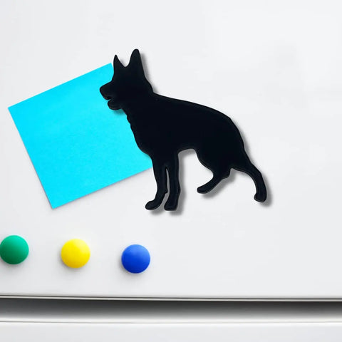The Chatelet Manufacturing German Shepherd Fridge Magnet in black holds a blue sticky note on a white fridge, above neatly lined green, yellow, and blue round magnets—a perfect gift for dog lovers. Made in the USA.