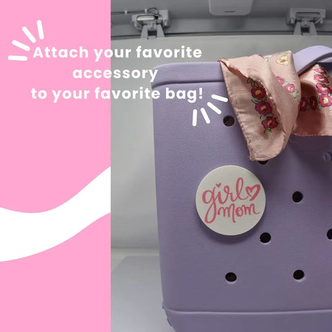 A purple Bogg Bag is decorated with a pink floral scarf and a Chatelet Manufacturing FRESHe BOGLETS - Girl Mom Charm (Pink and White), the perfect decorative accessory for your bag! Text: Attach your favorite accessory to your favorite bag!.