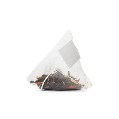 A close-up of a transparent, pyramid-shaped Glacier Bay Grey (Earl Grey Tropical Black Tea) bag from My Store, filled with loose tropical tea leaves and colorful pieces, set against a white background.