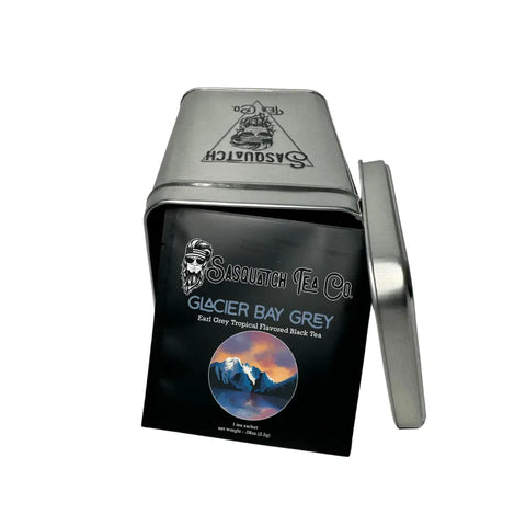 An open rectangular metal tin from My Store displays a packet of Glacier Bay Grey (Earl Grey Tropical Black Tea) featuring snowy mountains and a lake on the front.
