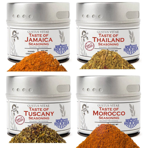 The Gustus Vitae Global Foodie Collection features four tins—Taste of Jamaica, Taste of Tuscany, Taste of Thailand, and Morocco—each with its unique spice blend displayed in front and finished with stylish silver tins and white-and-red labels.
