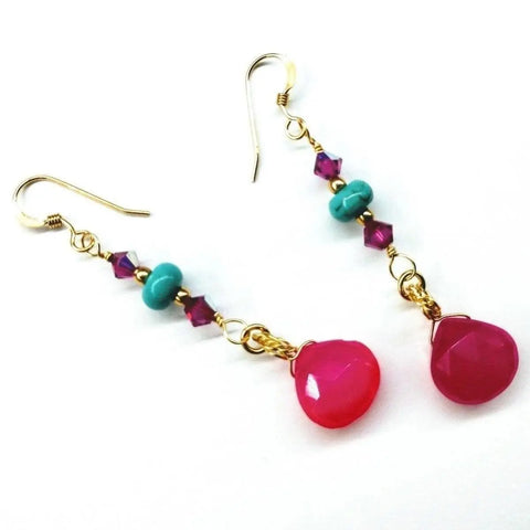 The Gold Filled Wire Wrapped Pink and Turquoise Gemstone Earrings by Alexa Martha Designs feature turquoise beads, purple crystals, and hot pink chalcedony teardrops on hooks, shown against a white background.