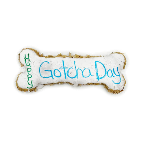 The Brewscuits Gotcha Day Jumbo Bone is an all-natural, bone-shaped dog treat with white icing and Happy Gotcha Day written in blue and green.