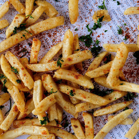 Crispy French fries seasoned with Gustus Vitae Gourmet Backyard BBQ Burgers & Fries Seasoning Set – Six Pack are arranged on a textured white surface with subtle printed text.