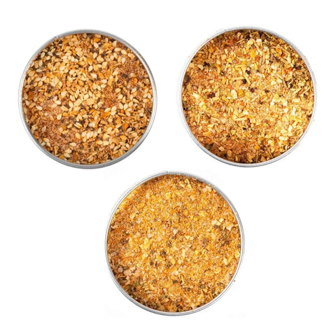 The Gustus Vitae Deluxe Chicken BBQ Seasonings Collection - 3 Pack features three all-natural spice tins with yellow and brown blends, arranged in a triangle on white—ideal for enhancing your next chicken BBQ.