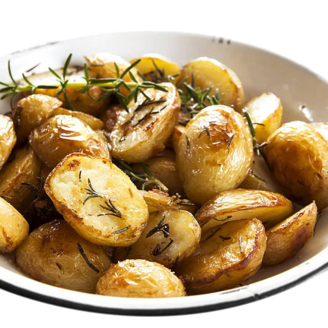 A white bowl of golden-brown roasted potatoes, garnished with fresh rosemary and topped with Gustus Vitaes Finishing Sea Salts Collection, adds a glossy, flavorful touch to this appetizing dish.