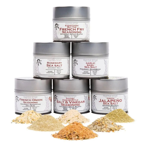 The Gustus Vitae Gourmet French Fry Seasoning Set - Six Pack is shown in a pyramid, each jar labeled with a unique flavor. All-natural, non-GMO artisanal blends are displayed in small piles on a white background.