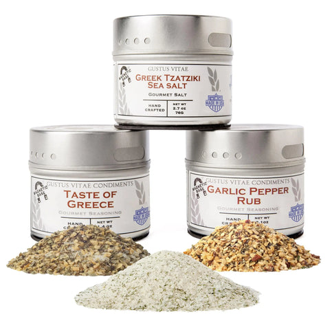 The Gustus Vitae Garlic Lovers Collection - 3 Tins is displayed with small piles of each vibrant seasoning in front, all set against a clean white background.