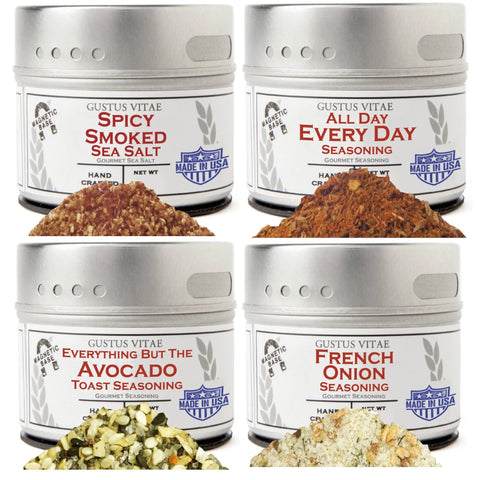 The Gustus Vitae Home Chef Flavor Kit features four tins: Spicy Smoked Salt, Every Day Seasoning, Everything But The Avocado Toast, and French Onion Seasoning, each showcased with a pile of seasoning in front.