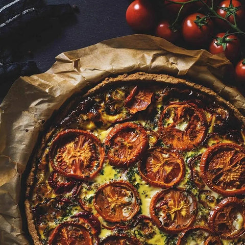 A tomato tart with a golden crust, topped with baked tomatoes, herbs, and Gourmet Seasonings Staples Collection | 4 Packs by vendor-unknown. Fresh vine tomatoes nearby inspire your pantry staples.