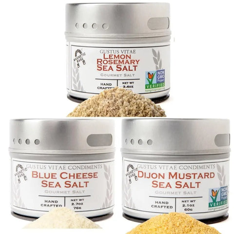 The Spring Party Essential Salts - 3 Pack by vendor-unknown includes lemon rosemary, blue cheese, and dijon mustard sea salts. Each tin displays a Non-GMO label and net weight, with small piles of salt shown in front.
