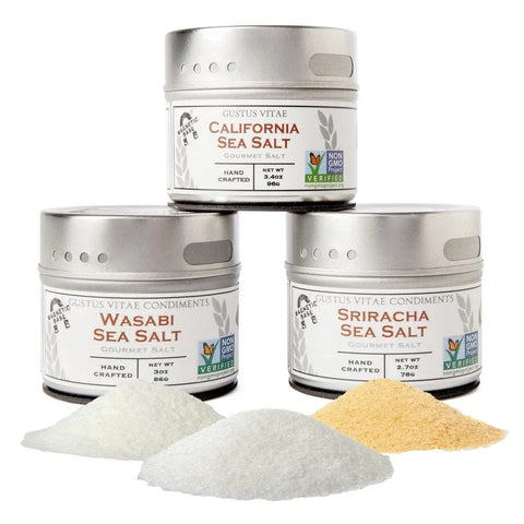 Three tins of Gustus Vitae Sushi Night Sea Salts are shown, with small piles of Sriracha Sea Salt and Wasabi Sea Salt in front of their respective tins.