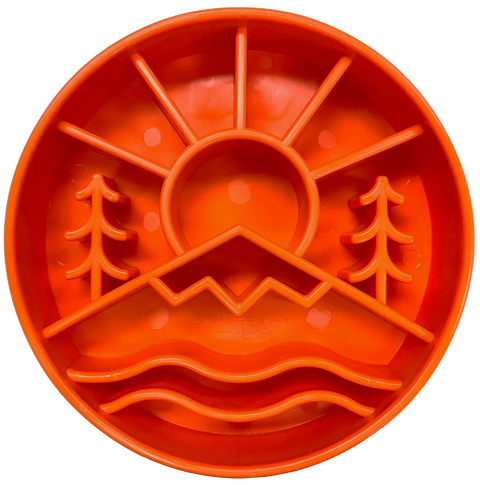 The SodaPup Great Outdoors Design EBowl is a round, orange silicone slow feeder bowl for dogs with raised dividers forming a sun, mountains, trees, and wavy water lines for enrichment in separate sections.
