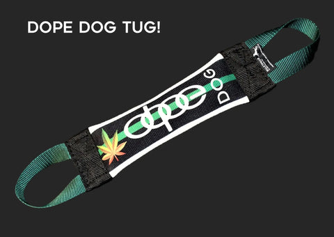 The Green Dope Dog Fire Hose Training Tug by Bulletproof Pet Products Inc is a black and green durable tug toy with DOPE DOG TUG! text and a marijuana leaf graphic, featuring two handles for interactive play.