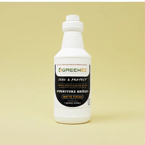 A white quart bottle of GreenEZ® Furniture Shield Water-Based Wood Sealer, made in the USA, stands upright on a light yellow surface with a matching yellow background.