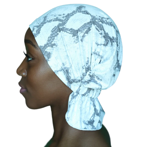 A person in profile wears a light-colored Scarves - Tammy Chemo Beanies® by Chemo Beanies®, featuring a gray abstract pattern, set against a black background.
