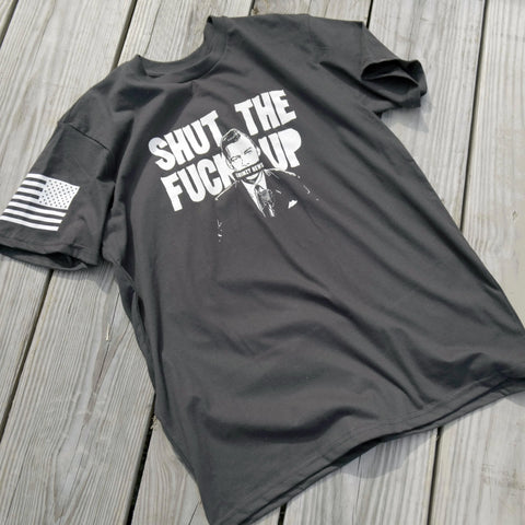 The American Lictor Collab Tee: Grimzy-STFU is a black, compacted ring-spun cotton T-shirt with “Shut the Fuck Up” over a suited man with taped mouth, American flag on the right sleeve. Size guide available.