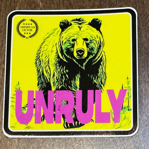 The Sticker: Grizzly - Unruly by American Lictor features a bold bear illustration on a bright yellow square, with UNRULY in large pink letters referencing the power of a .44 magnum and the American Lictor logo in the top left corner.