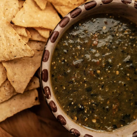 A bowl of green salsa, made with Gustus Vitae’s Ground Single Ingredient Pepper Collection, sits beside crunchy tortilla chips, ready for dipping.